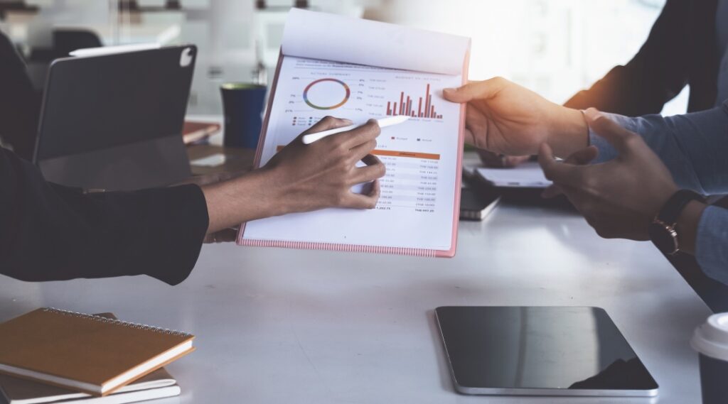 Business people around desk looking at page with graphs - representing Tax-loss harvesting