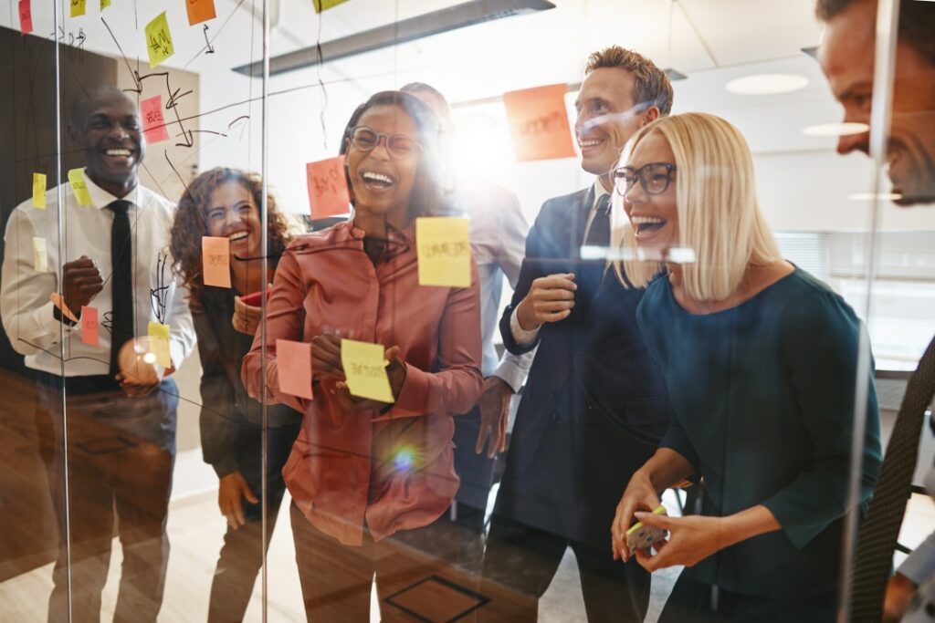 Laughing businesspeople looking at notes on office wall, representing Employee Stock Options.